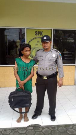 Tersangka (kiri) didampingi petugas memegang barang bukti tas dan isinya laptop. (Teddy Akbari/Sumut Pos)