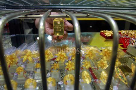 TRIADI WIBOWO/SUMUT POS--Seorang pemilik usaha menunjukan batangan emas di salah satu toko emas di pasar Pringgan Medan, Jumat (14/14)