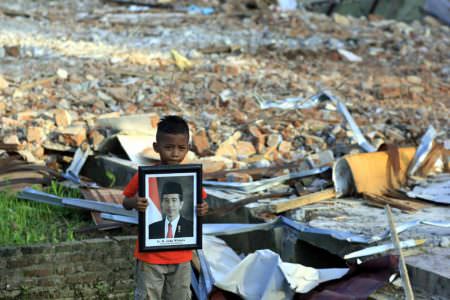 Muhammad Raja (11) memegang foto Presiden Joko Widodo di bangunan sekolahnya. Foto itu selamat akibat gempa 6,5 SR, Rabu 7 Desember lalu, sementara sekolahnya SD Negeri Tampui, Pidie Jaya, hancur.  ENO SUNARNO/RAKYAT ACEH