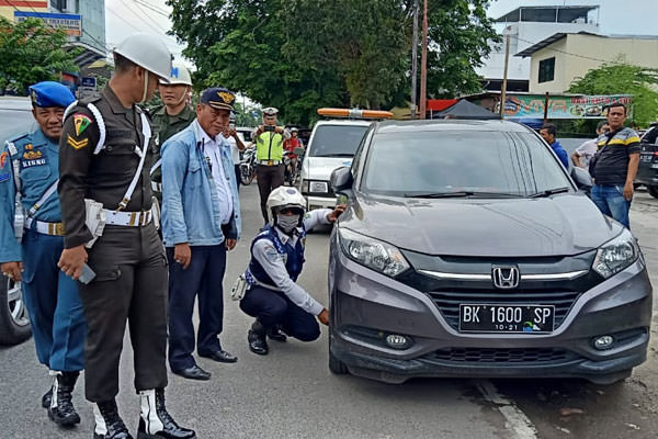 Sutan/sumutpos GEMBOSI: Petugas Dishub Kota Medan, dibantu Polisi dan TNI, menggembosi ban mobil di Jalan Sei Batanghari Medan yang parkir sembarangan.