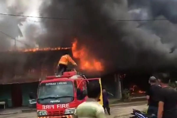 TERBAKAR: Petugas pemadam kebakaran berupa menjinakkan api yang melahap 7  rumah warga di Desa Marbau,  Labura, Kamis (31/1).