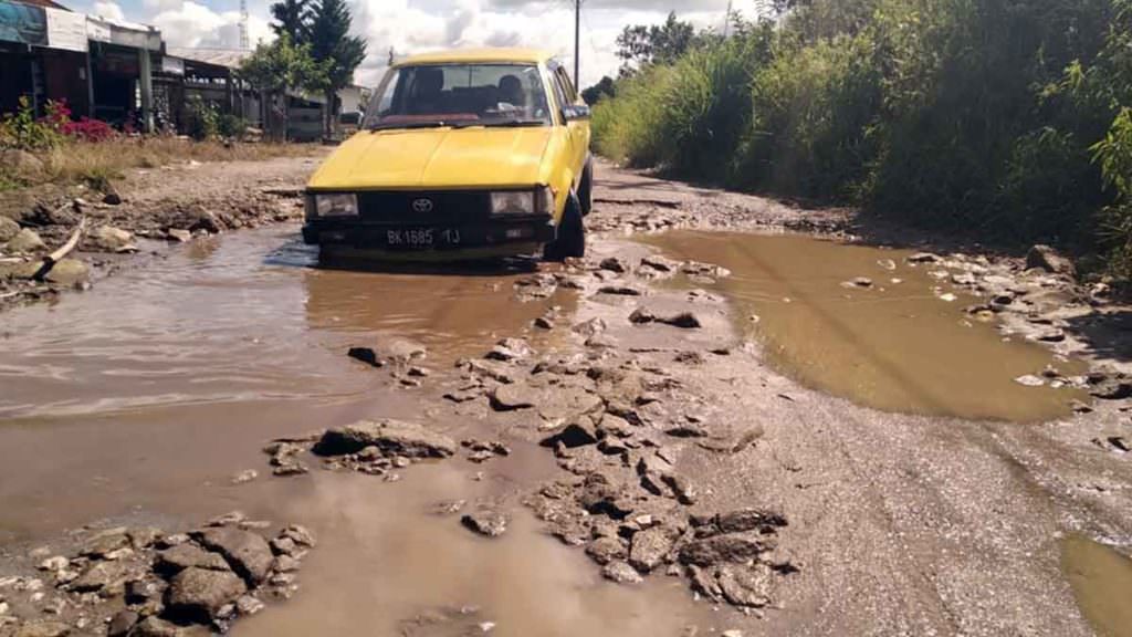 RUSAK PARAH: Kendaraan roda empat kesulitan melintasi Jalan Tanjung Beringin-PLTA Renun- Pangiringan yang rusak parah dan berlubang. 
RUDY SITANGGANG/SUMUT POS