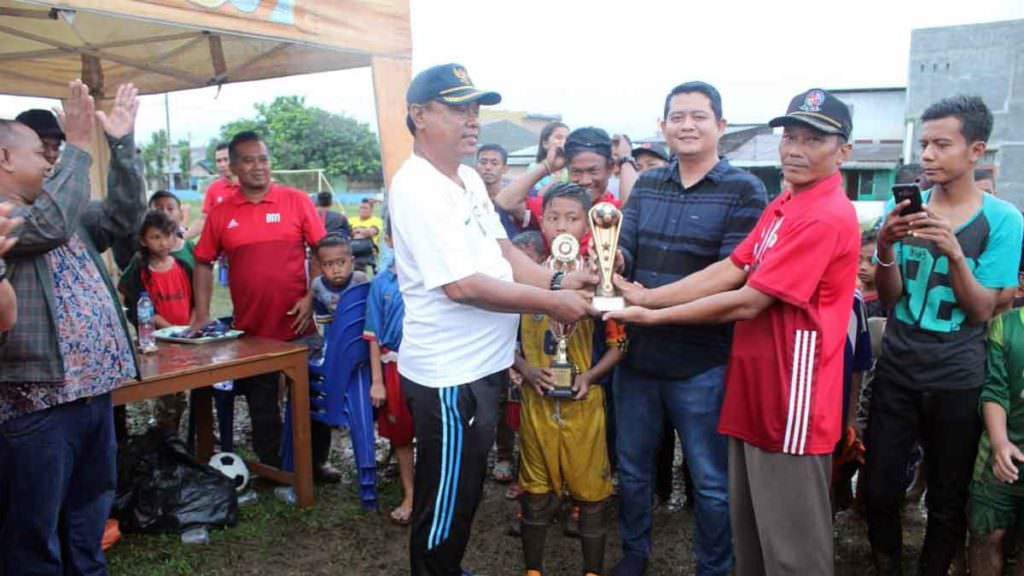 TROFI: Penyerahan trofi juara pertama oleh Kepala Desa Marindal 2 Jufriantono kepada Manajer Kompas FC.