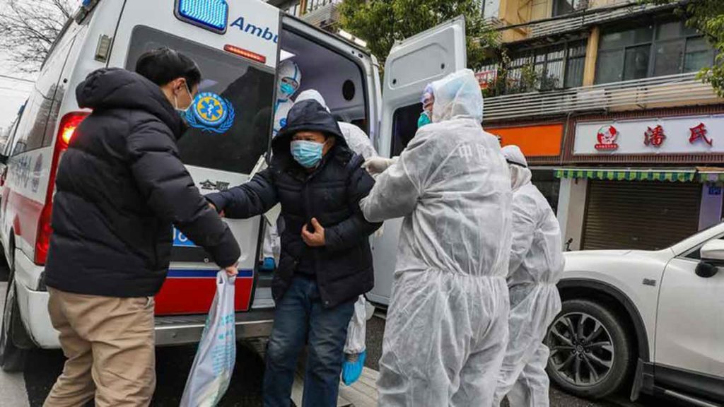 EVAKUASI: Petugas medis mengenakan pakaian pelindung membantu pasien turun dari ambulans untuk dirawat di rumah sakit di Wuhan, Provinsi Hubei, Tiongkok, Senin (27/1) waktu setempat. 