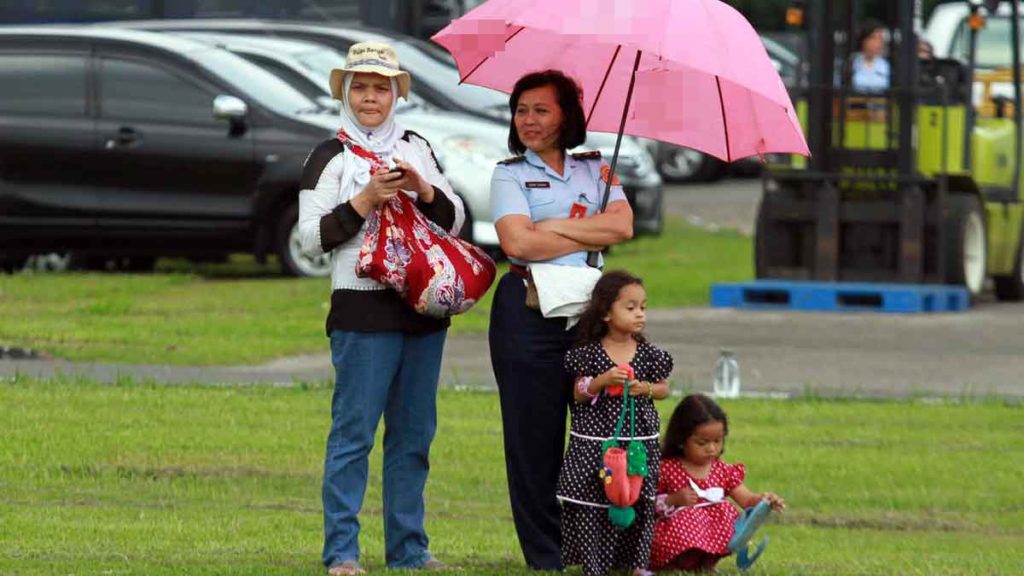 BERPAYUNG: Dua wanita menggunakan topi dan payung untuk melindungi dari terik matahari di Kota Medan, beberapa waktu lalu. Kota Medan akan disengat cuaca hangat karena memasuki musim pancaroba.