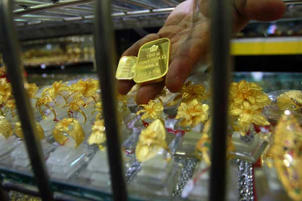 EMAS: Seorang pedagang menunjukkan sekeping emas yang dijual di toko miliknya. Imbas dari epidemi virus corona dari Tiongkok, harga emas dunia terkerek ke level tertinggi dalam dua pekan terakhir.