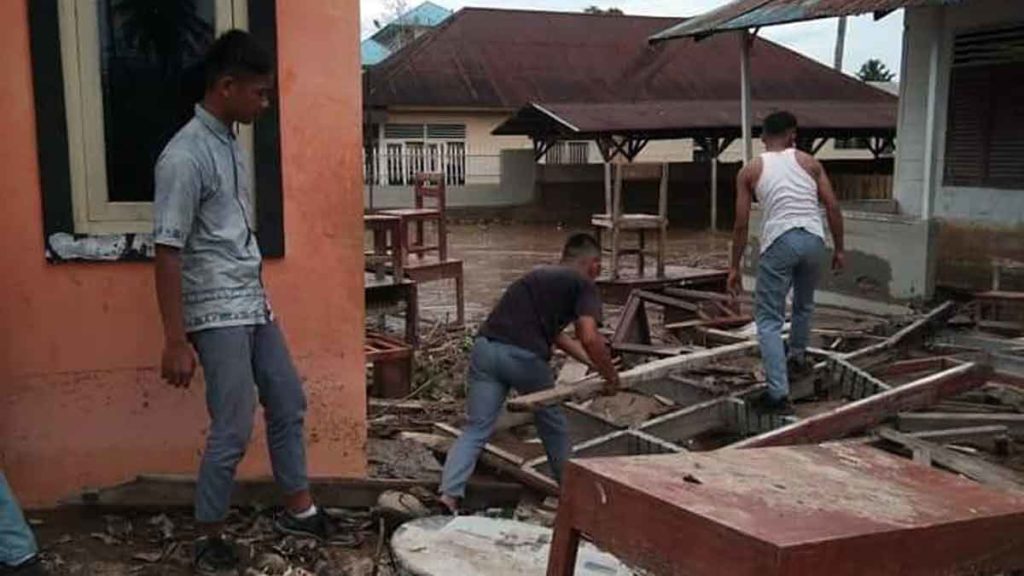 PASKABANJIR: Dua warga mengangkat balok kayu yang berserakan usai banjir bandang di Kabupaten Tapanuli Tengah, Jumat (31/1). 