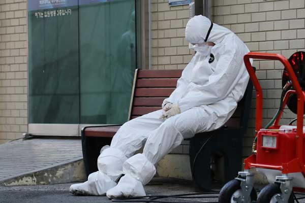 ISTIRAHAT: Seorang pekerja medis mengenakan pakaian proteksi di Daegu, Korea Selatan, sedang beristirahat, Minggu (23/2).