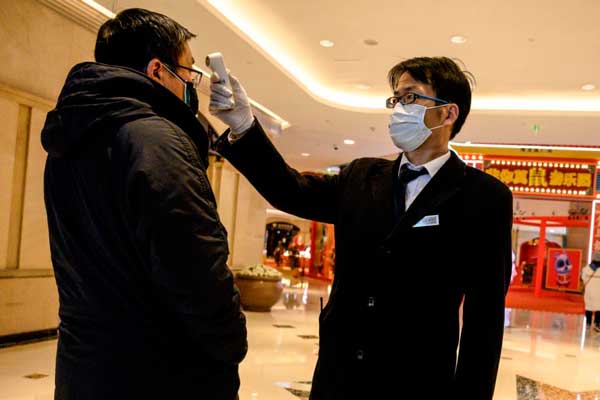 PERIKSA: Seorang petugas kesehatan memeriksa suhu tubuh seorang pengunjung di sebuah pusat perbelanjaan di Shanghai, Sabtu (8/2) lalu.