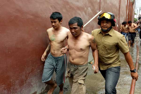 TERSANGKA Petugas menggiring sejumlah napi pascaaksi kerusuhan di Rutan Klas II B Kabanjahe, Kamis (13/2). Sebanyak 15 napi ditetapkan sebagai tersangka provokator, onar, dan pembakaran rutan.