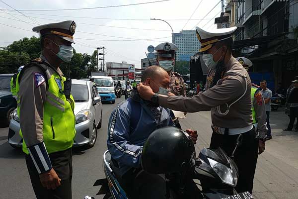 HADIAH MASKER: Kasatlantas Polrestabes Medan Kompol M Reza memasangkan masker kepada pengendara sepeda motor saat razia di Jalan Guru Patimpus, Selasa (10/3) siang.