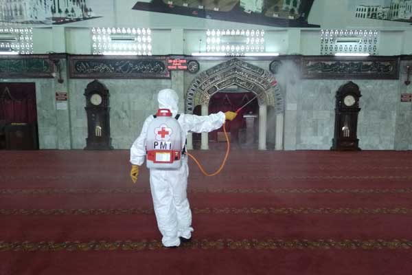 DISEMPROT: Petugas dari PMI Sumut menyemprotkan disinfektan di ruangan Masjid Agung Medan, sebelum pelaksanaan Salat Jumat (20/3).