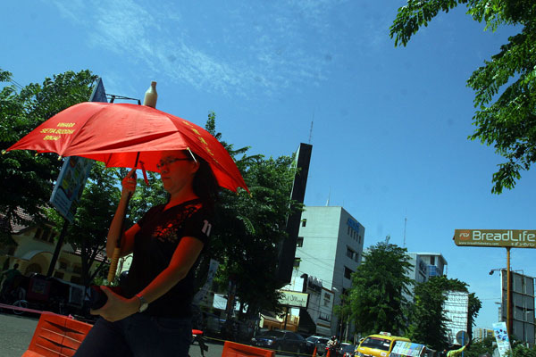 BERPAYUNG: Seorang wanita berlindung dari teriknya matahari di bawah payung di Jalan KH. Zainul Arifin Medan. Beberapa hari ini cuaca di Kota Medan panas menyengat. TRIADI WIBOWO/SUMUT POS