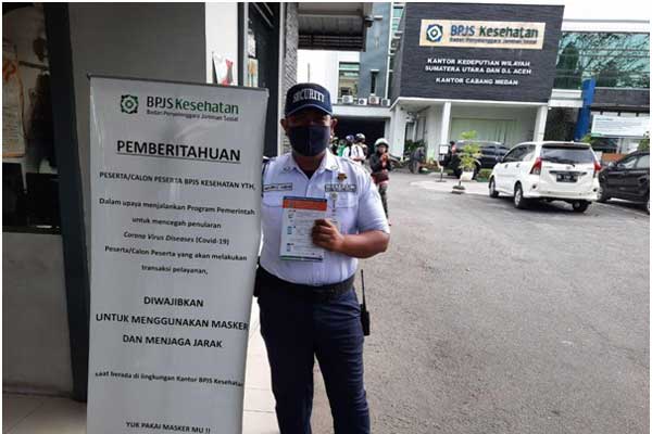 WAJIB MASKER: Satpam memajang banner pemberitahuan untuk wajib menggunakan masker saat memasuki Kantor BPJS Kesehatan Cabang Medan. M IDRIS/sumu tpos