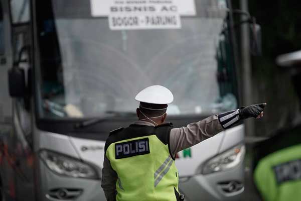 PUTAR BALIK Personel Polda Metro Jaya mengalihkan bus keluar tol Cikarang Barat di jalan tol Cikampek, Bekasi, Jawa Barat, Jumat (24/4). Buntut larangan mudik yang ditetapkan pemerintah, ribuan kendaraan disuruh memutar balik kembali ke asal. Poldasu juga akan menerapkan kebijakan yang sama.