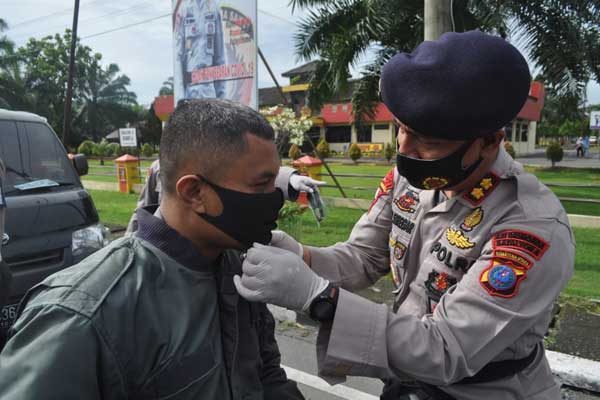 BAGIKAN: Danyon A Pelopor Sat Brimob Polda Sumut AKBP Boy Sutan Siregar saat membagikan masker kepada salah satu warga yang melintas di Jalan Soekarno Hatta, Binjai, Selasa (28/4).
