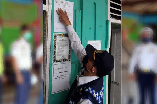 EDARAN: Petugas Dishub Medan menempel surat edaran di Pool Bus Medan.