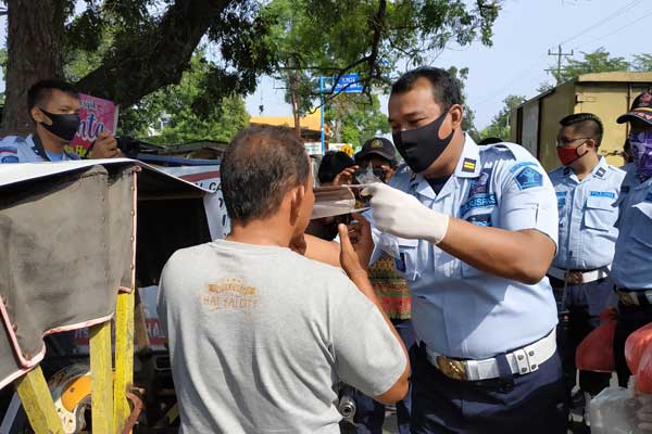 PAKAIKAN MASKER: KPLP Binjai, Rinaldo Tarigan memakaikan masker kepada abang becak yang mangkal di depan Kantor Lapas Binjai, Jalan Jenderal Gatot Subroto, Kelurahan Limau Mungkur, Binjai Barat