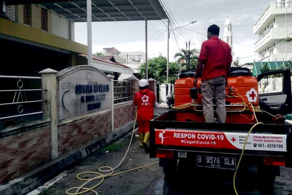 PENYEMPROTAN: Relawan PMI Sumut melakukan penyemprotan cairan disinfektan di Kecamatan Medan Timur, Sabtu (18/4) pagi.