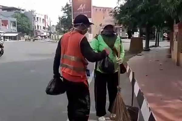BERBAGI: Seorang juru parkir berbagi sembako kepada petugas kebersihan Pemko Binjai. tedi/Sumut Pos