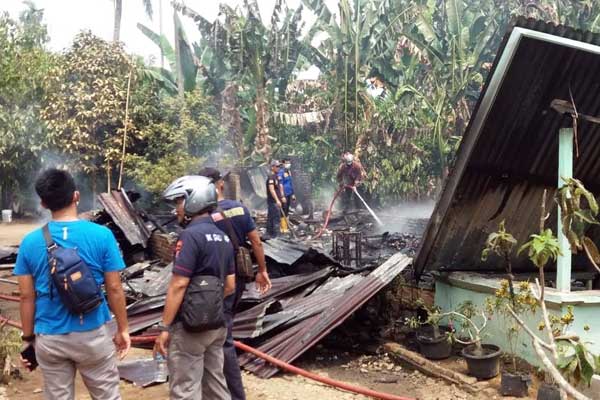 PADAMKAN: Petugas pemadam kebakaran dan warga memadamkan bara api yang melalap rumah korban.