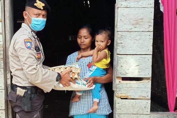 BANTU: Anggota Bhabinkamtibmas Polres Tebingtinggi, Bripka Elpin Malau ketika menyambangi rumah warga memberikan bantuan sembako imbas Covid -19.