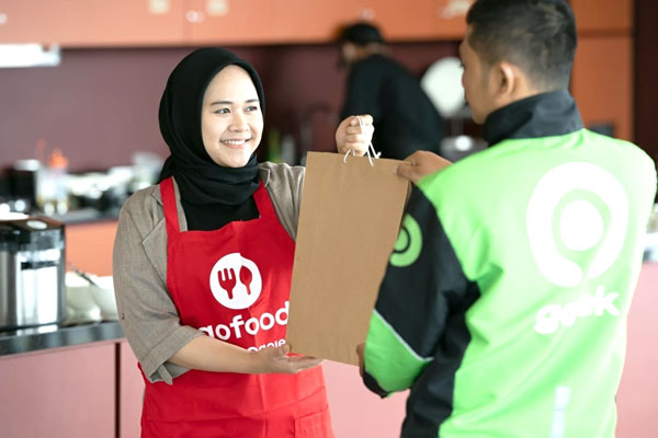 TUKAR: Seorang mitra driver di Medan menukarkan voucher ‘Paket Makan Keluarga’ disalah satu merchant GoFood yang berpartisipasi dengan paket makanan berisi tiga porsi makanan sehat berisi nasi, lauk pauk, dan sayuran..