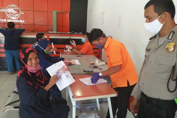 TERIMA: Siti Aisah warga Kelurahan Sidiangkat Kecamatan Sidikalang Kabupaten Dairi saat menerima uang BST Covid-19 Kemensos tahap I di Kantor Pos di Jalan Sisingamangaraja Sidikalang. RUDY SITANGGANG/SUMUT POS