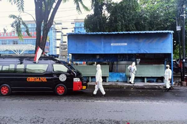 SEMPROT: Sat Brimob Poldasu menyemprot disinfektan di halte di Medan.