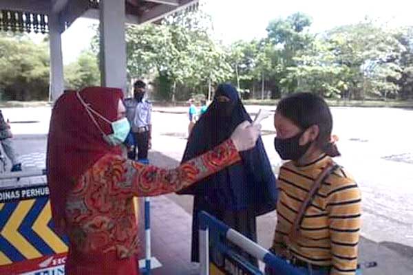 PERIKSA: Petugas kesehatan dari Dinkes Tebingtinggi melakukan pengukuran suhu tubuh kepada penumpang bus.