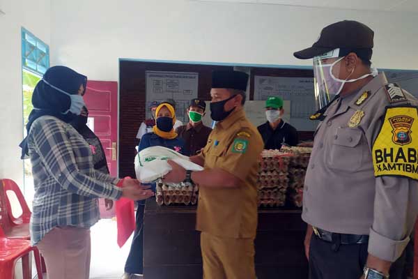 SERAHKAN: Kepala Desa Pelawi Selatan menyerahkan bansos Bupati Langkat kepada warga terdampak pandemi virus Corona.  ILYAS EFFENDY/ SUMUT POS