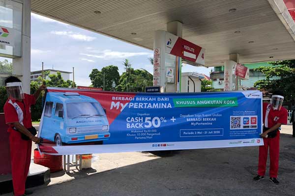 SPANDUK: Karyawan SPBU Pertamina saat menunjukkan spanduk cashback untuk para supir Angkot.