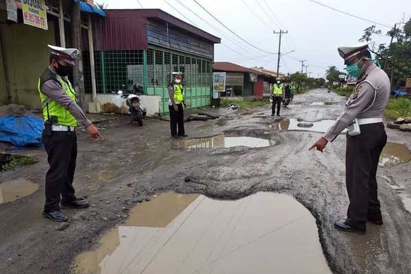 KUPAK KAPIK: Sejumlah petugas kepolisian saat meninjau dan mengamankan Jalan Perintis Kemerdekaan/Besar Hamparan Perak, Kabupaten Deli Serdang yang kondisinya sudah kupak kapik alias rusak parah, Rabu (10/6).