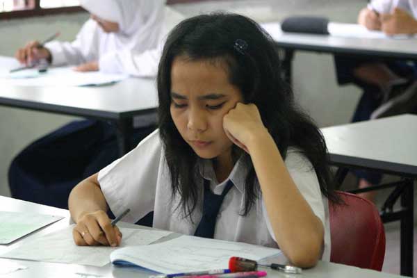 BELAJAR: Seorang siswi SMP sedang belajar di kelas sebelum pendemi Covid-19.