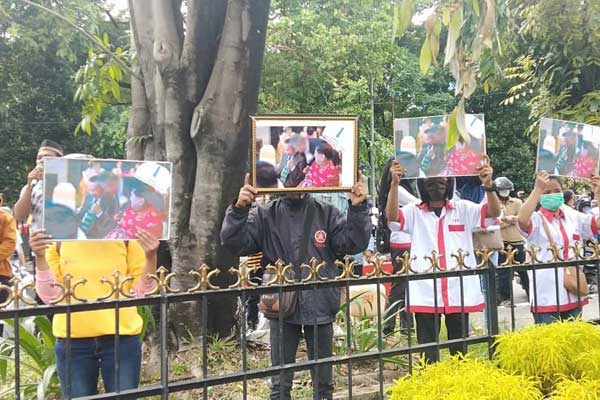 BENTANG SPANDUK: Ratusan pekerja PT Opal Coffee Indonesia aksi demonstrasi, membentangkan spanduk dan foto bergambar terdakwa Dr Benny Hermanto di PN Medan, Kamis (18/6).