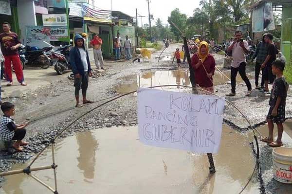 manding-di-jalan-hamparan-perak MEMANCING: Warga Hamparanperak memancing di lubang Jalan besar Hamparanperak. Aksi ini sebagai bentuk rasa kecewa warga terhadap pemerintah karena tak kunjung memperbaiki jalan tersebut.
