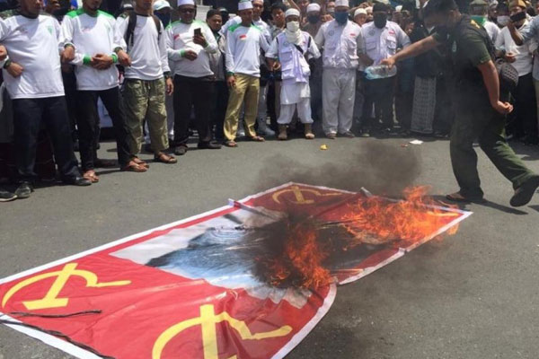 BAKAR: Para pendemo membakar bendera bersimbol Partai Komunis Indonesia (PKI) saat unjukrasa di Lapangan Merdeka Medan, Minggu (5/7).