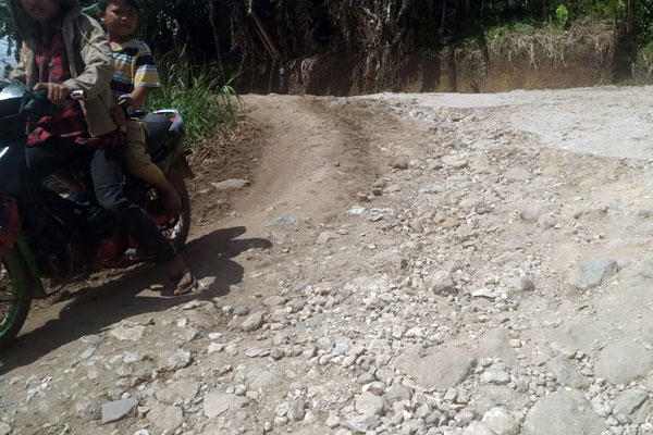 RUSAK: Pengendara sepeda motor melintasi salah satu titik badan jalan yang rusak menuju Desa Parbuluan 3 ke Parbuluan 2 Kecamatan Parbuluan, Kabupaten Dairi.RUDY SITANGGANG/SUMUT POS.