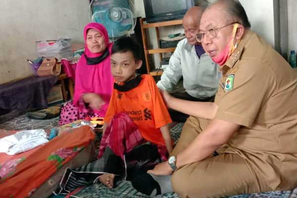 KUNJUNGI: Bupati Soekirman didampingi Kadis Kesehatan, dr Bulan Simanungkalit mengunjungi Aris Munandar (15) bocah Disabilitas mengalami kelumpuhan, Senin (27/7).