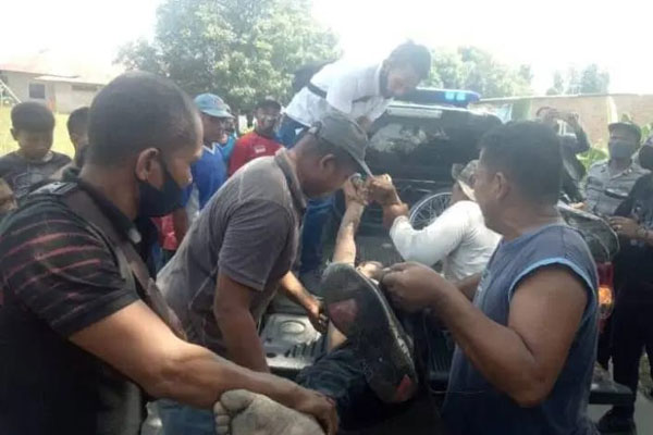 EVAKUASI: Petugas kepolisian dibantu warga mengevakuasi jenazah pelaku Curanmor yang tewas didalam parit setelah menabrak pohon.
