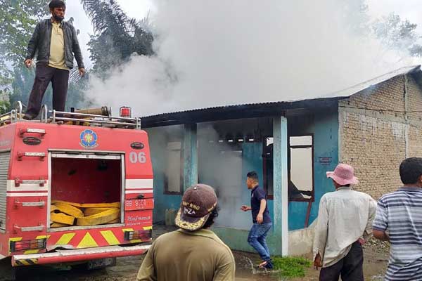 TERBAKAR: Petugas Damkar Pemkab Dairi berusaha memadamkan api yang melalap rumah Ranto Sihite, di Desa Bintang Kecamatan Sidikalang Kabupaten Dairi, Sabtu (18/7).