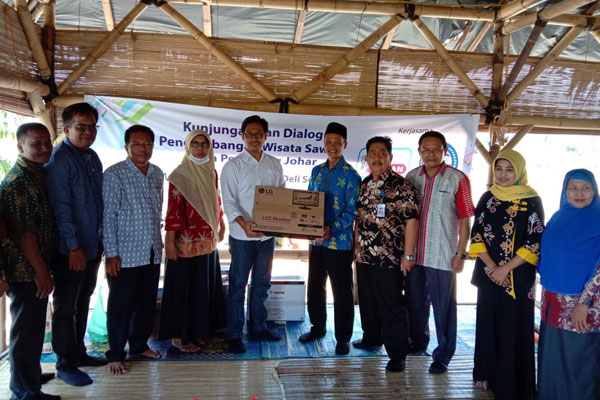 BANTUAN: Ketua KORAN DS Indra Prawira, ST, MM memberikan bantuan komputer dan buku bacaan untuk Wisata Sawah kepada Kades Pematang Johar, Kamis (24/7).