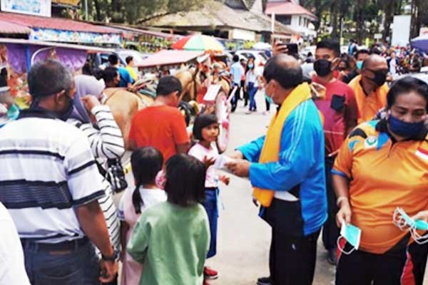 BAGIKAN: Bupati Terkelin Brahmana dan Ketua DPRD Karo Iriani Tarigan membagikan masker kepada wisatawan yang berkunjung ke Berastagi, Minggu (19/7).