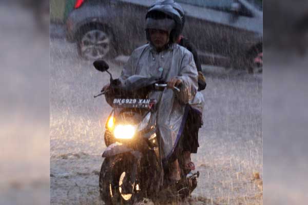 HUJAN: Seorang pengendara menggunanakan mantel hujan saat hujan deras di Kota Medan. Hujan mengguyur Kota Medan pada Rabu (12/8) dinihari, menyebabkan sejumlah wilayah di Kota Medan terendam banjir.