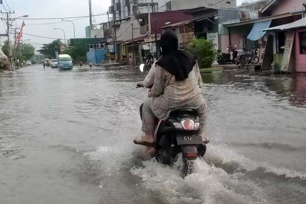 BANJIR ROB: Pengendara melintasi genangan air dari banjir Rob di kawasan Medan Utara, baru-baru ini.