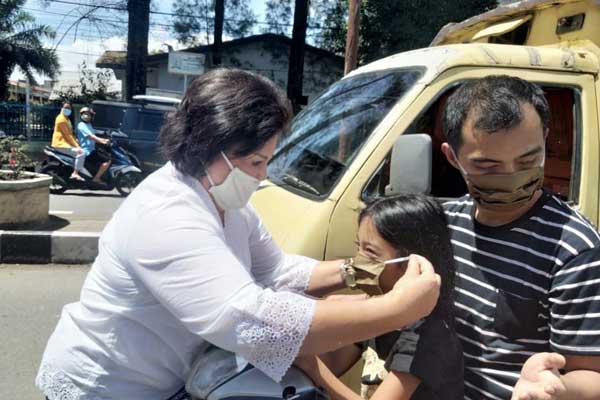 PAKAIKAN: Cory S Sebayang memakaikan masker pada seorang anak yang sedang melintas.