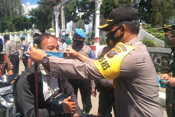 PAKAIKAN MASKER: Kapolres Karo AKBP Yustinus Setyo Indriyono memakaikan masker kepada seorang pengendara.SOLIDEO/SUMUT POS.