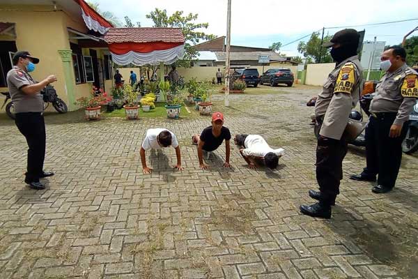 DIHUKUM: Tiga orang warga dihukum melakukan push-up saat razia oleh petugas penanganan covid-19. Warga diketahui kedapatan tak memakai masker saat beraktivitas di tempat umum.