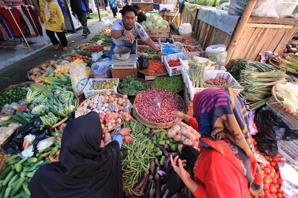 TRANSAKSI:  Pedagang sedang bertransaksi pembelian bahan pangan di pasar tradisional, belum lama ini.