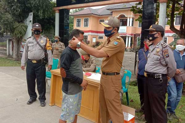 PASANG MASKER: Camat Rambutan Marwansyah Harahap disaksikan Kapolsek Rambutan AKP H Samosir memasang masker kepada warga yang terjaring razia yustisi.